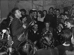 Pete Seeger entertaining Eleanor Roosevelt (center), honored guest at a racially integrated Valentine's Day party marking the opening of a Canteen of the United Federal Labor, CIO, in then-segregated Washington, D.C., 1944.[6]