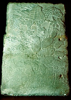 The founding of the Aztec capital Tenochtitlan; An eagle representing Huitzilopochtli, which exhales the atl-tlachinolli (war symbol), is perched on a nopal cactus. Teocalli of the Sacred War, sculpted in 1325.