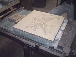 A limestone plate with a negative map of Moosburg in Bavaria is prepared for a lithography print.