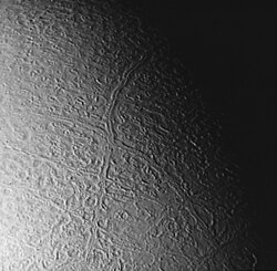 Cantaloupe terrain viewed from 130,000 km by Voyager 2, with crosscutting Europa-like double ridges. Slidr Sulci (vertical) and Tano Sulci form the prominent "X".