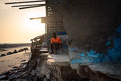 A man looking out over the beach from a building destroyed by high tides in Chorkor, a suburb of Accra. Sunny day flooding caused by sea level rise, increases coastal erosion that destroys housing, infrastructure and natural ecosystems. A number of communities in Coastal Ghana are already experiencing the changing tides.