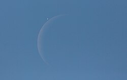 venus next to a crescent moon in the blue daytime sky