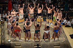 Sumo wrestlers form around the referee during the ring-entering ceremony.