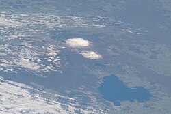 Taupō Volcano is mainly under the large blue Lake Taupō seen from its north from low earth orbit with beyond to its south the smaller Lake Rotoaira, and the active stratovolcanoes of Tongariro and Ruapehu covered in this picture with snow.