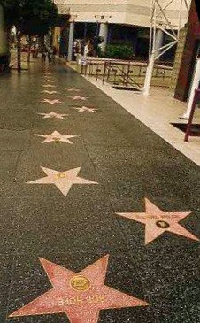 Charcoal sidewalk featuring two rows of alternating stars, one row full and the other with gaps. No pedestrians.