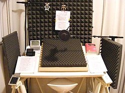 Example of an audio studio for professional readings. The studio is surrounded in sound baffle panels to mitigate reverberation from the speaker, allowing the microphone to pick up clearer audio.