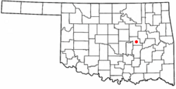 A white map of Oklahoma with a red dot in the center