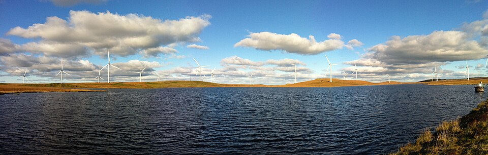 A panoramic view of the United Kingdom's Whitelee Wind Farm with Lochgoin Reservoir in the foreground.
