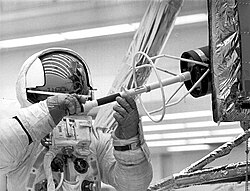 Haise practices removing the fuel capsule from its transport cask mounted on the LM. The real cask sank unopened into the Pacific Ocean with its radioactive contents.