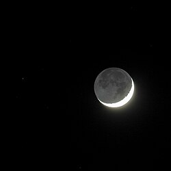 The night side of the Moon, illuminated by earthshine, becomes visible next to the narrow crescent (11 percent, age of the Moon = 3.3 days) with ash-grey moonlight.