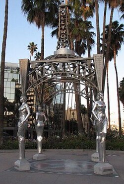 side view of the gazebo showing the ground, the structure, the caryatids, the spire, and the letters "Hollywood". The top of the spire extends beyond the image