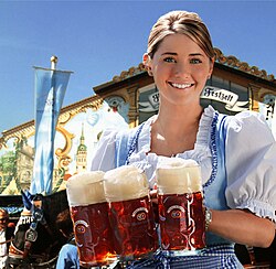 An Oktoberfest waitress wearing a dirndl and carrying beer mugs.