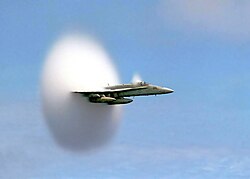 U.S. Navy F/A-18 approaching the speed of sound. The white halo is formed by condensed water droplets thought to result from a drop in air pressure around the aircraft (see Prandtl–Glauert singularity).[26]