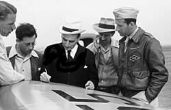 Theodore von Kármán sketching out a plan on the wing of an airplane. From left to right: Clark B. Millikan, Martin Summerfield, von Kármán, Frank J. Malina and pilot, Capt. Homer Boushey.