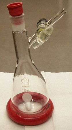 A pear-shaped Schlenk flask. The flask's sidearm contains a greased stopcock valve, and the flask is capped with a Suba•Seal septum that has not been turned down.