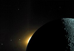 A color enhanced photograph from the Moon of a range of components of the Solar System. The three dots at the lower left are from left to right the planets Saturn, Mars, and Mercury, and in the middle of the picture rises the Sun's corona over the dark limb of the Moon, which is from the right lit by earthshine.