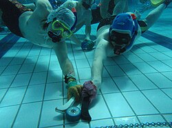 Two underwater hockey players competing for the puck