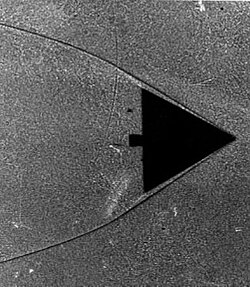 Delta wing in wind tunnel. The shadows form as the indices of refraction change within the gas as it compresses on the leading edge of this wing.