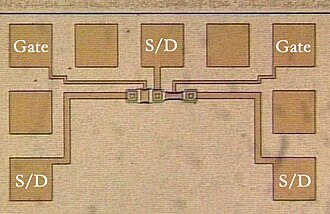 Photomicrograph of two metal-gate MOSFETs in a test pattern. Probe pads for two gates and three source/drain nodes are labeled.