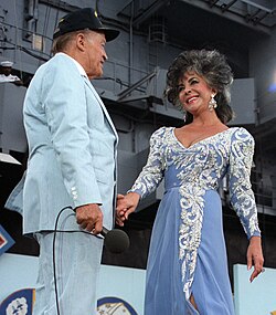 Taylor with Bob Hope performing in a United Service Organization show aboard the training aircraft carrier USS Lexington during the celebration of the 75th anniversary of naval aviation in 1986.