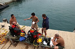A dive team listens to a safety brief from their dive supervisor