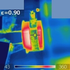 Materials with higher emissivity appear closer to their true temperature than materials that reflect more of their different-temperature surroundings. In this thermal image, the more reflective ceramic cylinder, reflecting the cooler surroundings, appears to be colder than its cubic container (made of more emissive silicon carbide), while in fact, they have the same temperature.