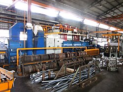 A horizontal hydraulic press for hot aluminum extrusion (loose dies and scrap visible in foreground)