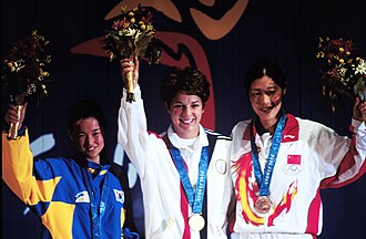 Gold medallist Nancy Johnson (centre) of the U.S., raises her hands with silver medallist Kang Cho-hyun (left), of South Korea, and bronze winner Gao Jing (right), of China, during the first medal ceremony of the 2000 Olympic Games.