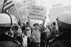 A man holding a sign that reads "deport all Iranians" and "get the hell out of my country" during a protest of the Iran hostage crisis in Washington, D.C. in 1979