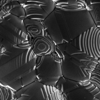 Silver crystal growing on a ceramic substrate.