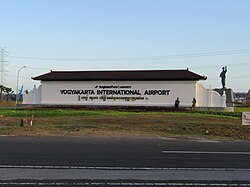 Yogyakarta International Airport signage from front view, with a name marker in the shape of a pyramid, the name in English, and Javanese script.