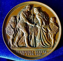 The reverse shows the couple in medieval costumes in front of 3 squires carrying the shields of Prussia, Germany, and Schleswig-Holstein.