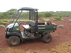  Small two-seater vehicle with a canopy for the passengers and an open load bed for cargo.