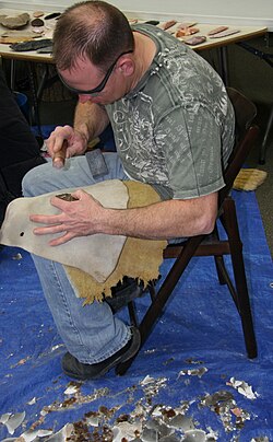 A leather leg guard protects the knapper from being injured by the edges of the flint.