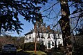 A large two story colonial frame house, five windows wide and three deep. It has a hip roof and two chimneys. The second floor windows have Christmas greenery below them, and the word Noel has been hung below the central window and above the front door.