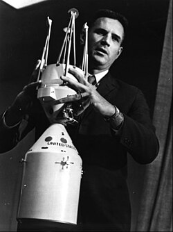 A 1962 model of the first LEM design, docked to the command and service module. The model is held by Joseph Shea, the key engineer behind the adoption of lunar orbit rendezvous mission logistics.