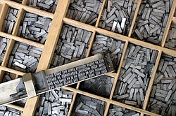 A case of cast metal type pieces and typeset matter in a composing stick