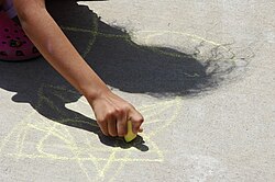 Child drawing with sidewalk chalk