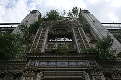 The front facade of the theatre, now overgrown with weeds.