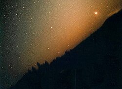 The zodiacal light, parts of which are reflected by interplanetary dust, which in turn originates in part from collisions of asteroids.