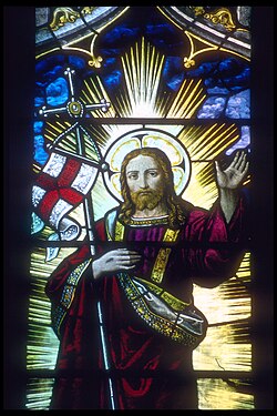 Jesus supporting an English flag and staff in the crook of his right arm depicted in a stained glass window in Rochester Cathedral in Rochester, Kent, England