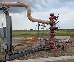 Photo of a wellhead in front of a prairie background