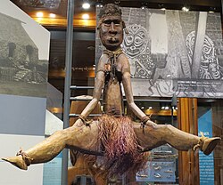 Wooden status of a woman sitting with her legs open