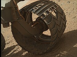 Close-up view of a well-worn wheel on the surface, which also shows the Morse code pattern for JPL.