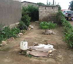 Groundwater pollution in Lusaka, Zambia, where the pit latrine in the background is polluting the shallow well in the foreground with pathogens and nitrate