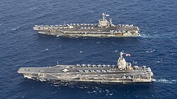 Aerial view of USS Gerald R. Ford (bottom), a ship of the new Gerald R. Ford class, alongside USS Harry S. Truman (top), a ship of the previous Nimitz class