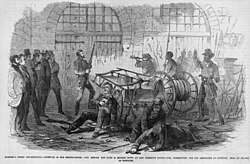 Illustration of the interior of the Fort immediately before the door is broken down. Note hostages on the left.