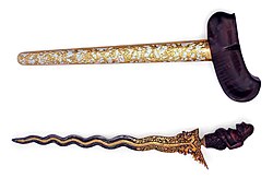 A decorative kris with a figure of Semar as the handle. The blade has thirteen luk.