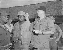 Wayne signing the helmet of Pfc. Fonzell Wofford during a visit at Chu Lai, South Vietnam, in June 1966
