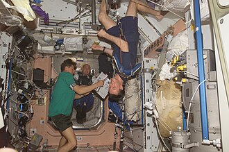 Astronauts on the ISS in weightless conditions. Michael Foale can be seen exercising in the foreground.